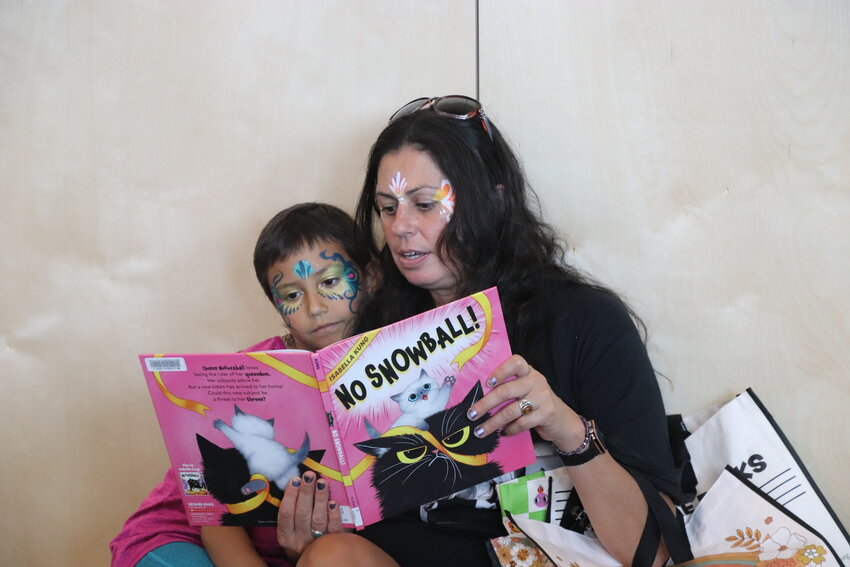 Sadie Madrid and her daughter Indigo, 9, read “No Snowball!” after getting their faces painted at the grand opening of the Castle Rock Library. Madrid said she is excited about the new library amenities.